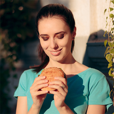 Junge Frau hat einen Burger in den Händen - Verena Krais - Gesundheits-coaching und Training - intuitives Essen- Ernährung - Schlaf